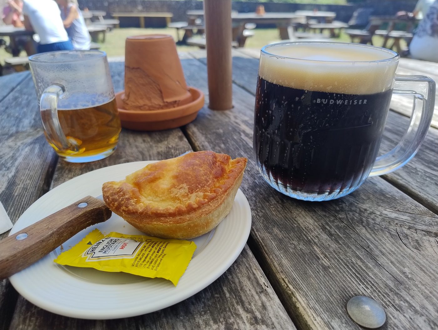 A pie with a dark beer and an ale on a garden table